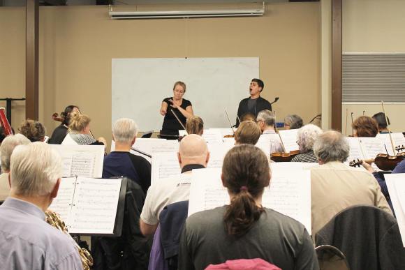 MCO conductor, Andrea Bell, conducts a rehearsal in the CMU conference room. Baritone soloist Nathan Dyck is singing beside Andrea.